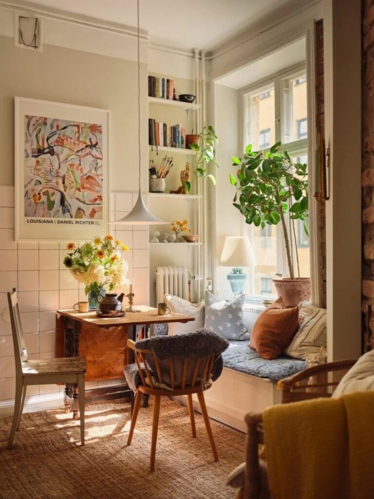 Small wooden dining table with mismatched grey and mid-century modern chairs in bright room.