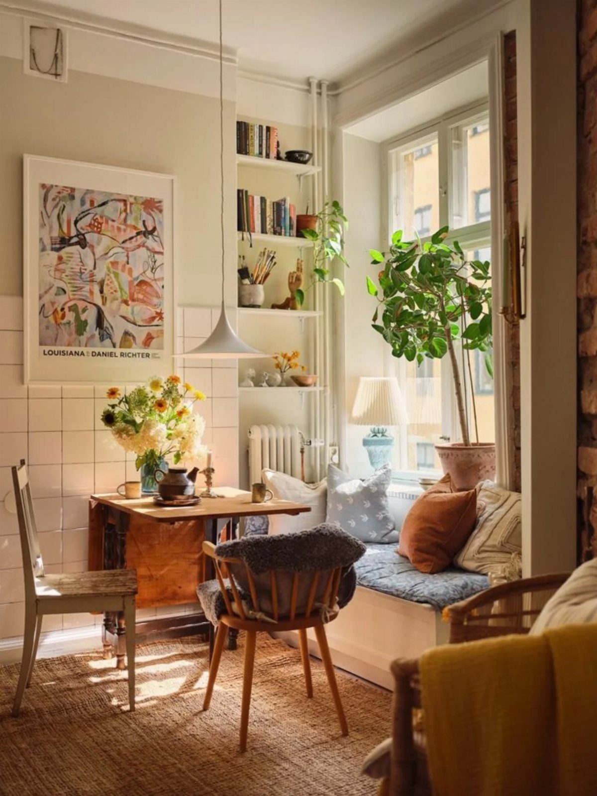 Small wooden dining table with mismatched grey and mid-century modern chairs in bright room.
