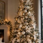 Decorated Christmas tree with gold and silver ornaments and white flowers in a living room.