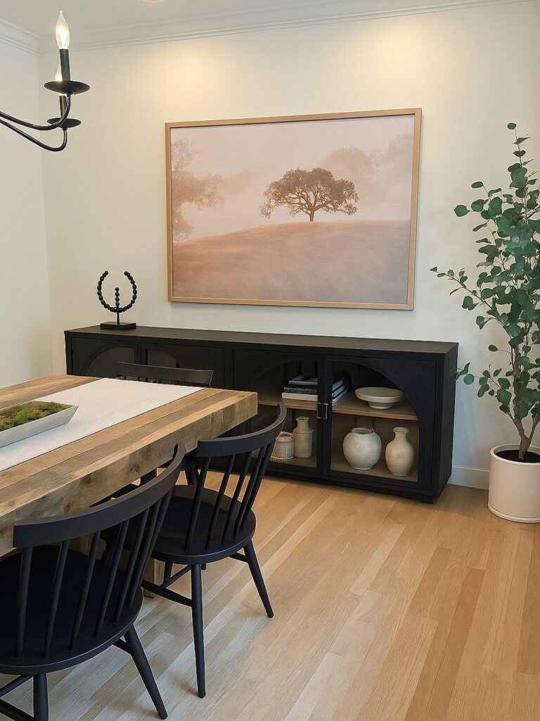 Black dining room buffet sideboard decorated with vases under a large landscape painting.