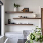 Dark wood floating shelves above a white sideboard with minimalist kitchen decor.