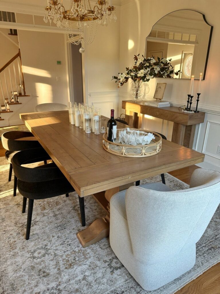 Wooden dining table and chairs anchored by a large grey patterned area rug.