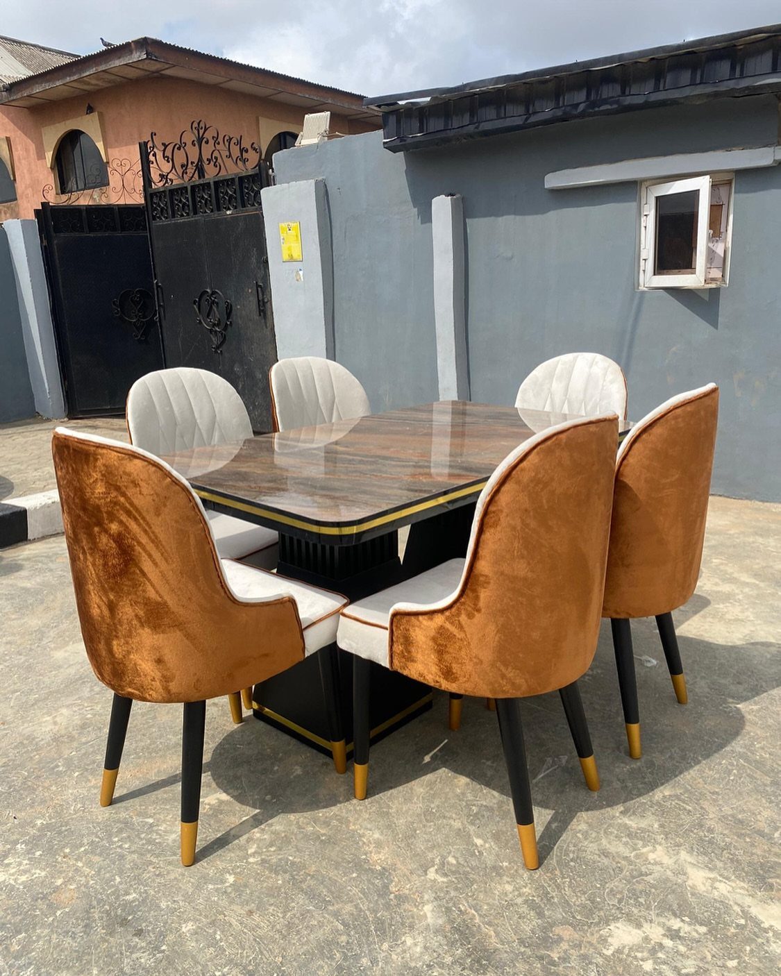 Marble dining table with mixed tan and white upholstered chairs outdoors