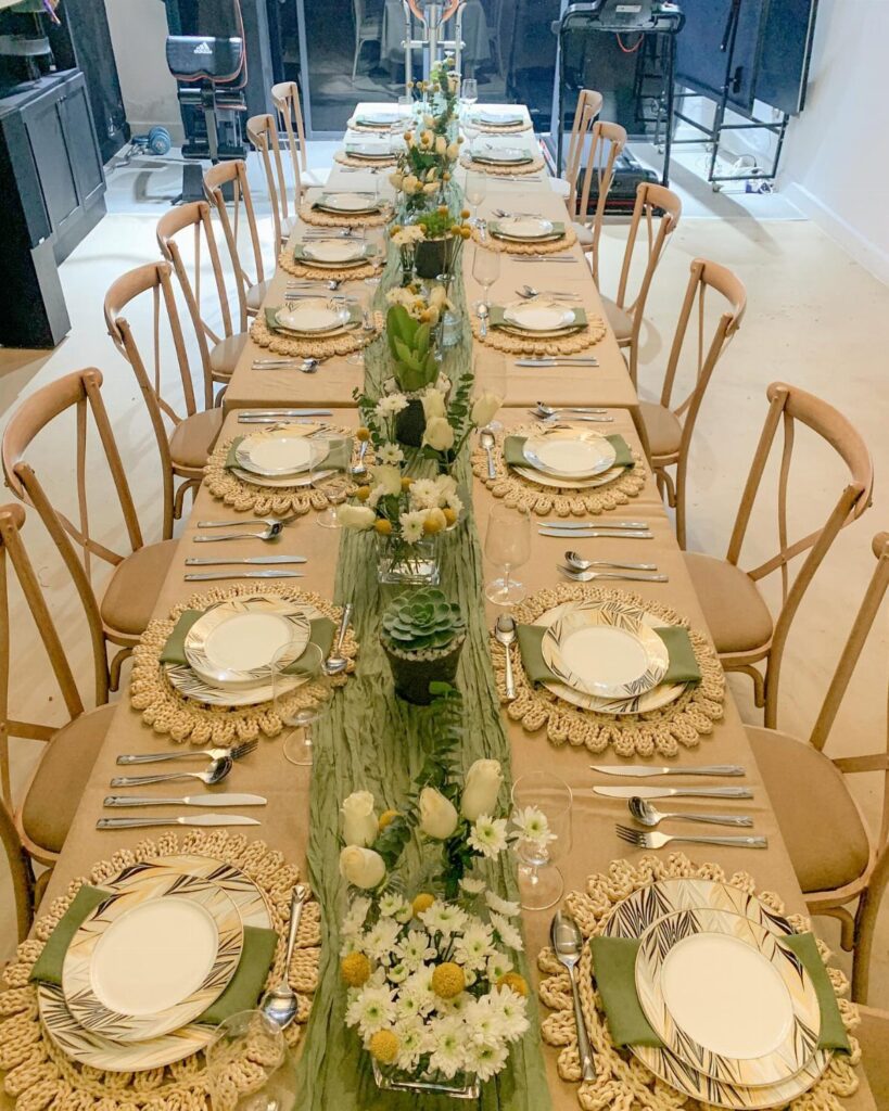 Elegant dining table set with green runner, white flowers, and beige placemats.