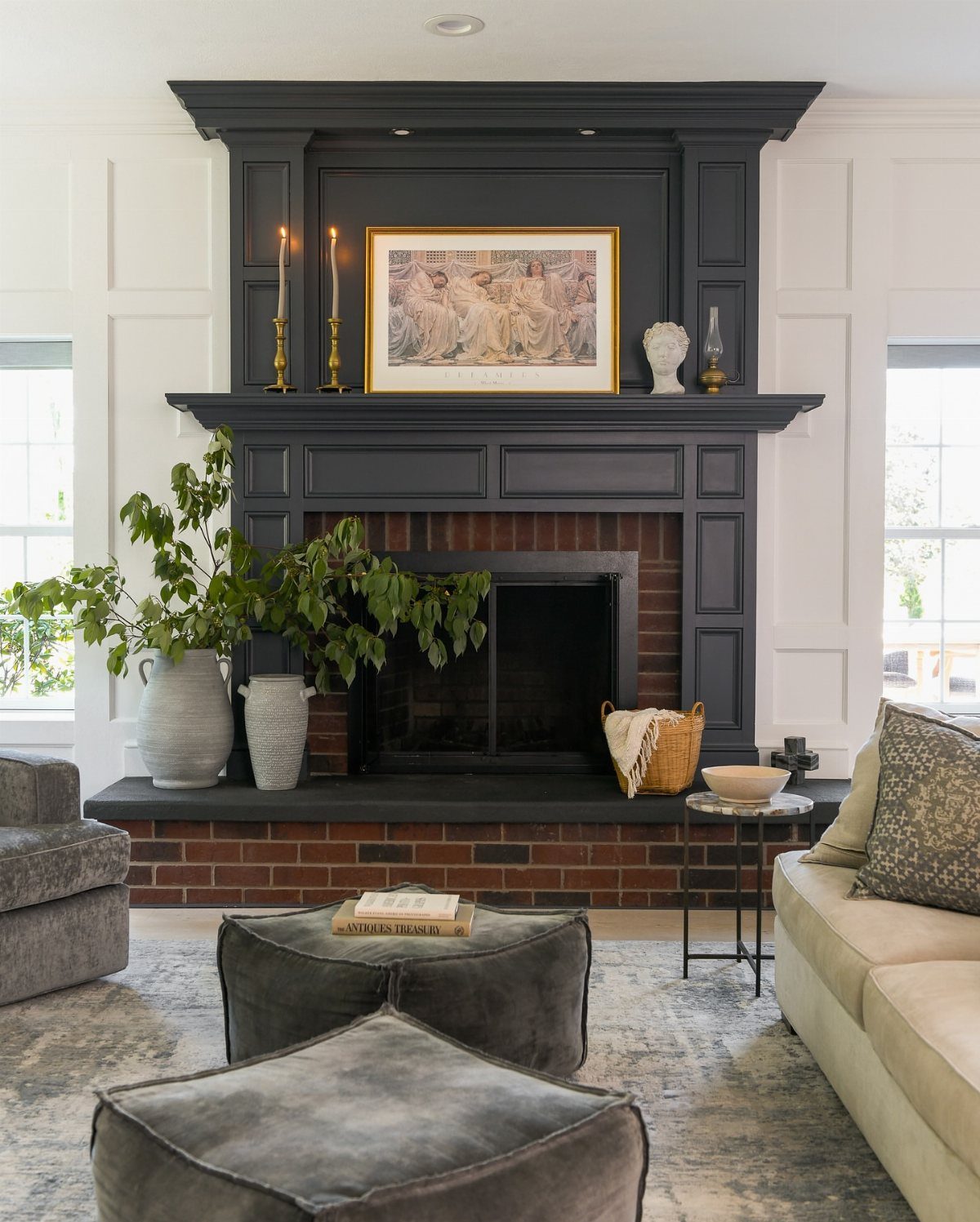 Large framed artwork centered on a black fireplace mantel with gold candlesticks.