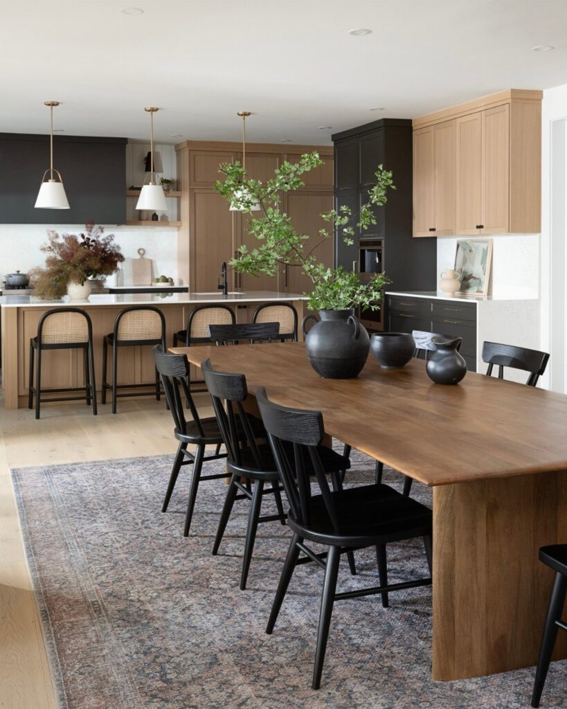 Wooden dining table with black chairs in an open concept kitchen and dining area.