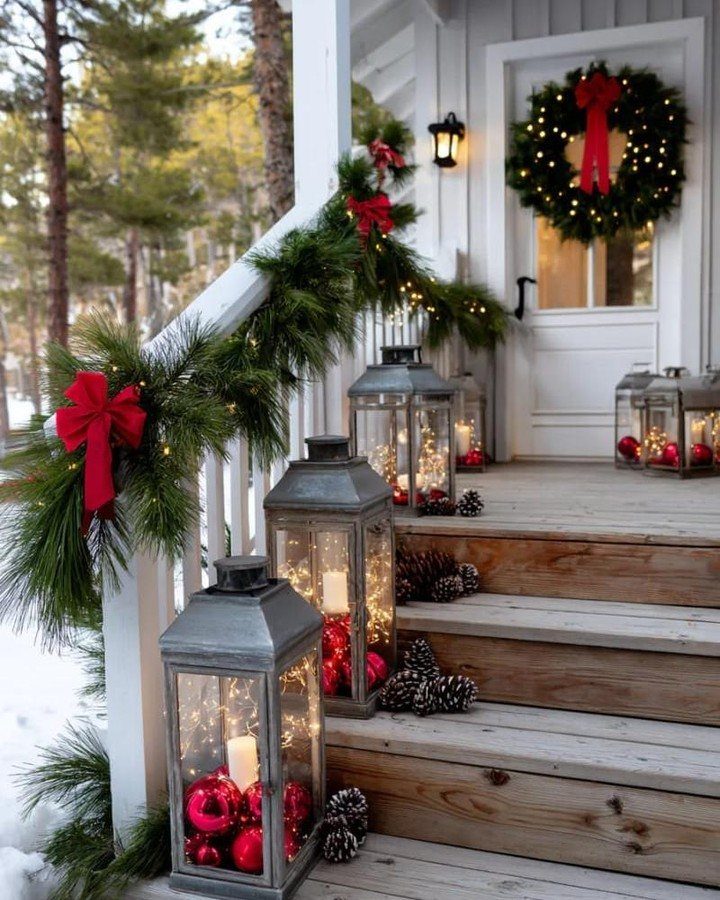 Green pine garland with red bows and lights decorating a white porch railing.