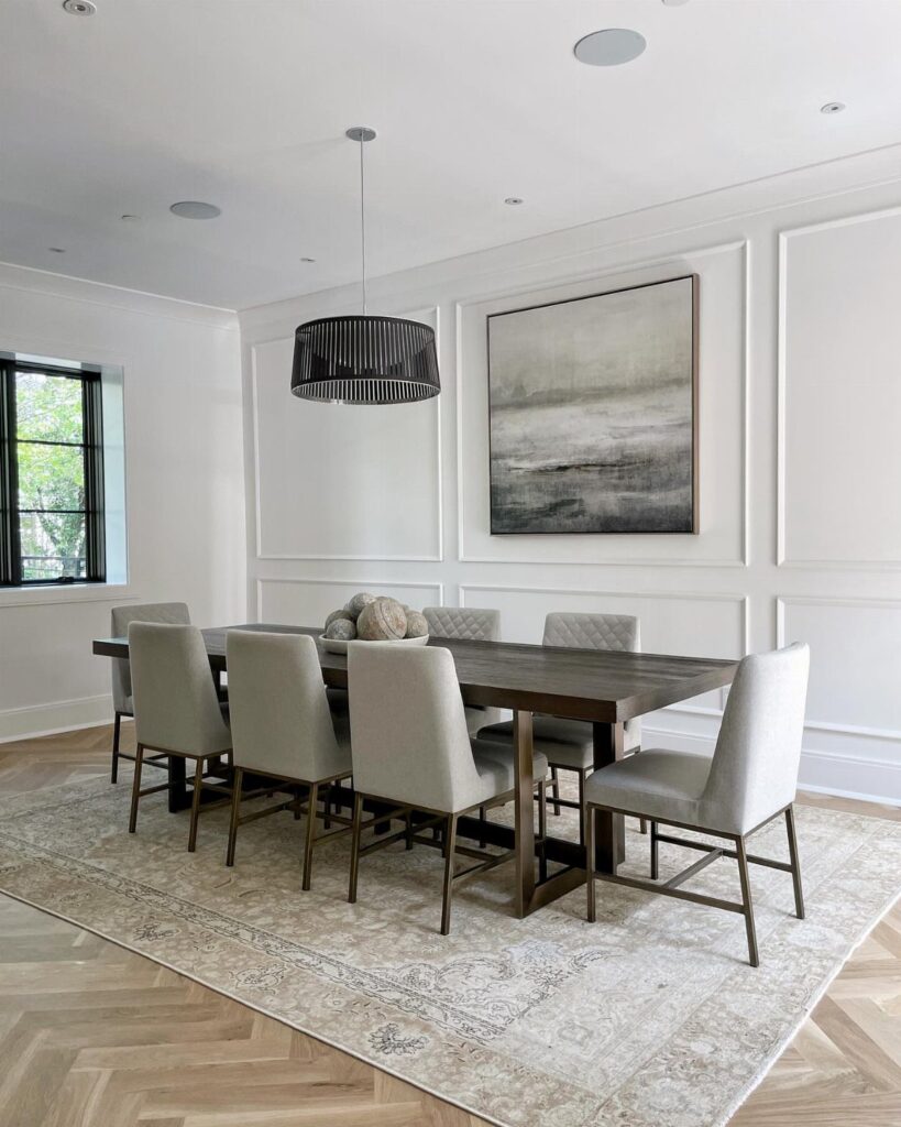 Rectangular wooden dining table and grey chairs on a matching rectangular patterned rug.