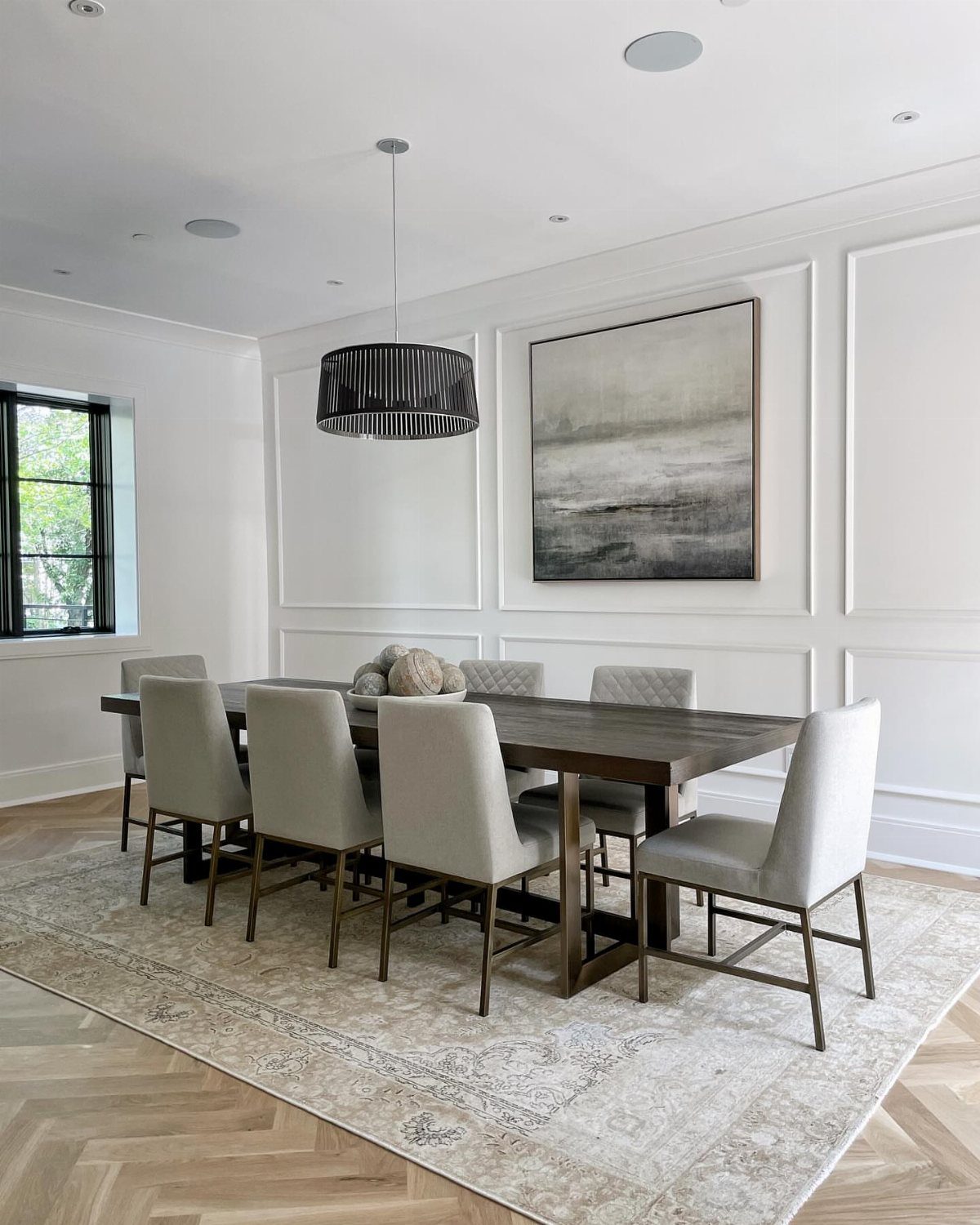 Rectangular wooden dining table and grey chairs on a matching rectangular patterned rug.