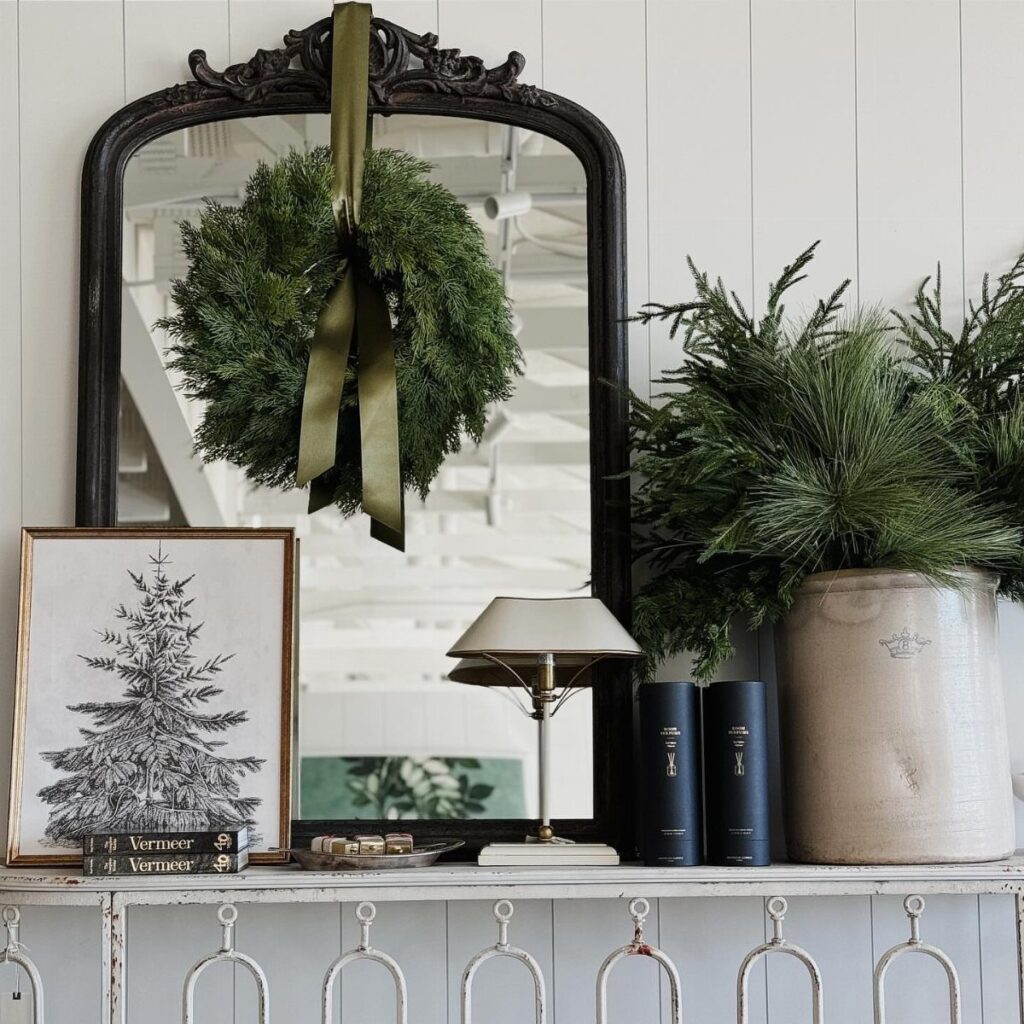 Green evergreen wreath with gold ribbon hanging on a black ornate mirror