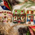 Iced cookies shaped like Victorian shops surrounded by pinecones and evergreen branches.
