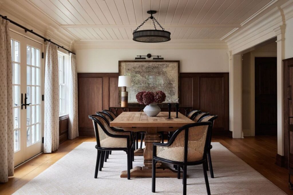 Dining room with dark wood wall paneling, wooden table, and cane back chairs.